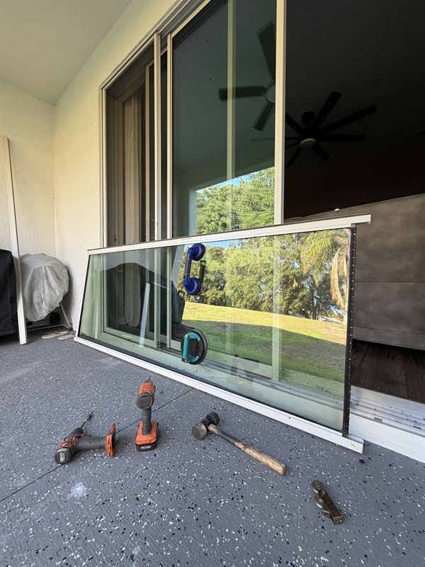 Real Speedy sliding door restoration: glass panel lifted out of its frame with drill, hammer, and pry bar laid out on the patio at a Central Florida home