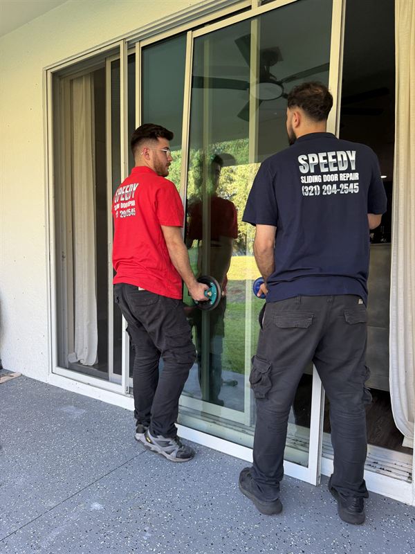 Speedy technicians using professional vacuum suction cups to safely lift a heavy sliding glass door panel