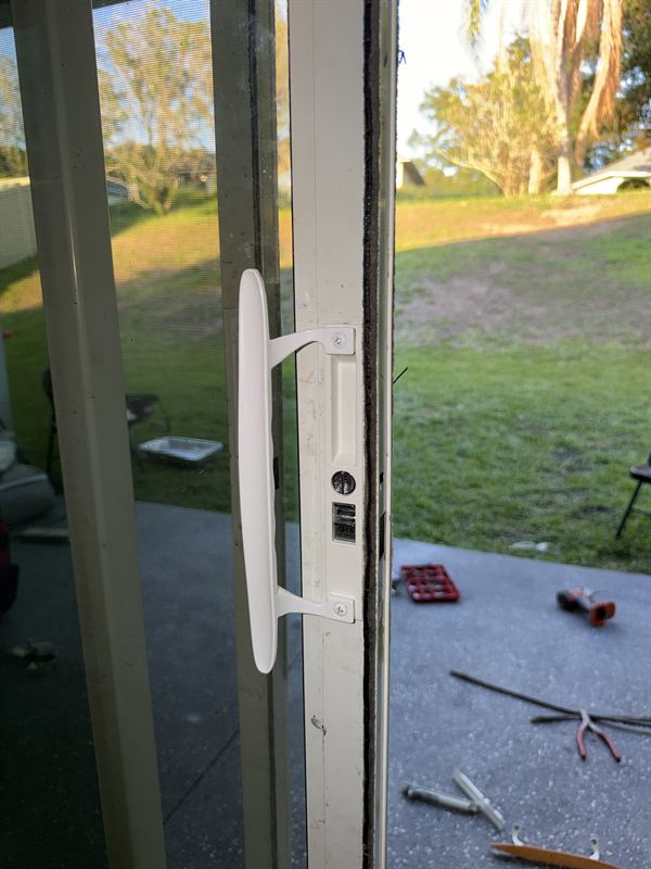 Speedy technician servicing a sliding door lock and handle mechanism on a Central Florida patio door