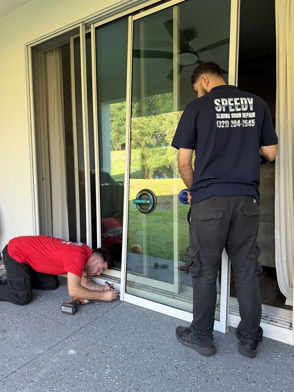 Two Speedy technicians in SPEEDY polos working together on a heavy sliding glass door restoration in Central Florida