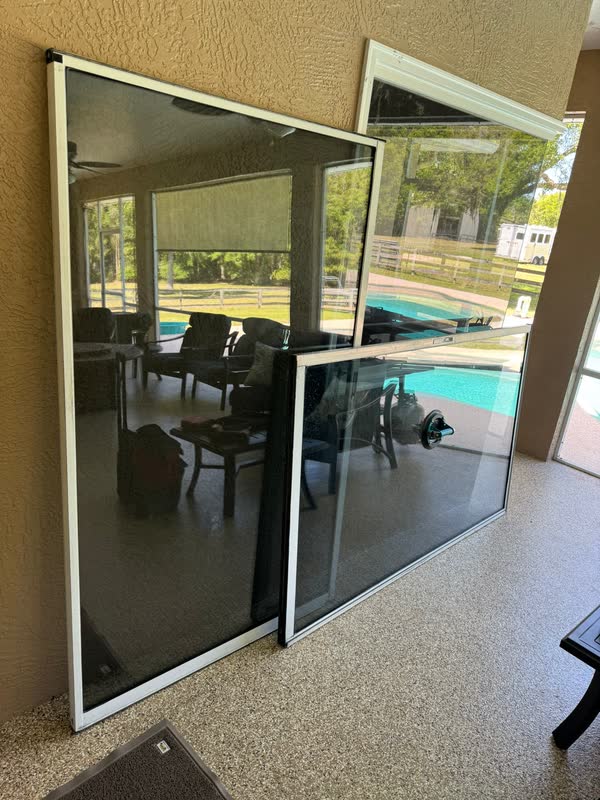 Several sliding glass door panels removed and leaning against the wall during a multi-door restoration at a Central Florida pool home
