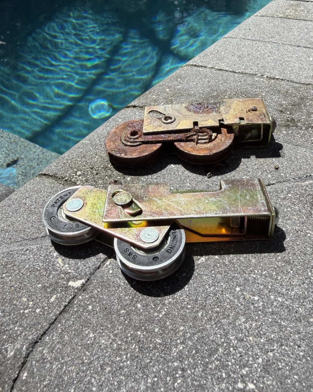 Rusted worn sliding door roller beside a new stainless sealed-bearing roller by a Central Florida pool — Speedy Sliding Door Repair