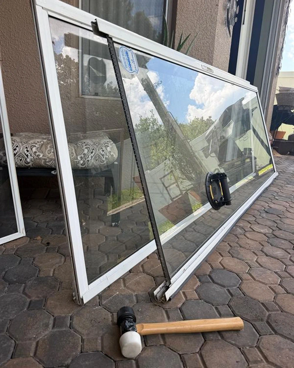 Large sliding glass door panel lifted out and leaning on a paver patio — Speedy Sliding Door Repair, Central Florida