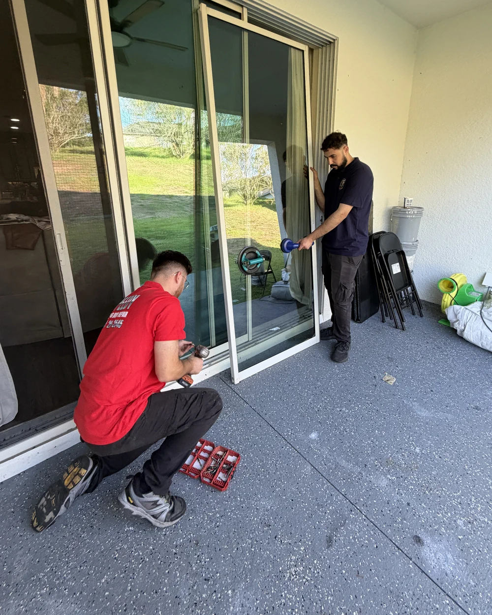 Two Speedy technicians working a sliding glass door together on a Central Florida lanai — one drilling, one on the panel
