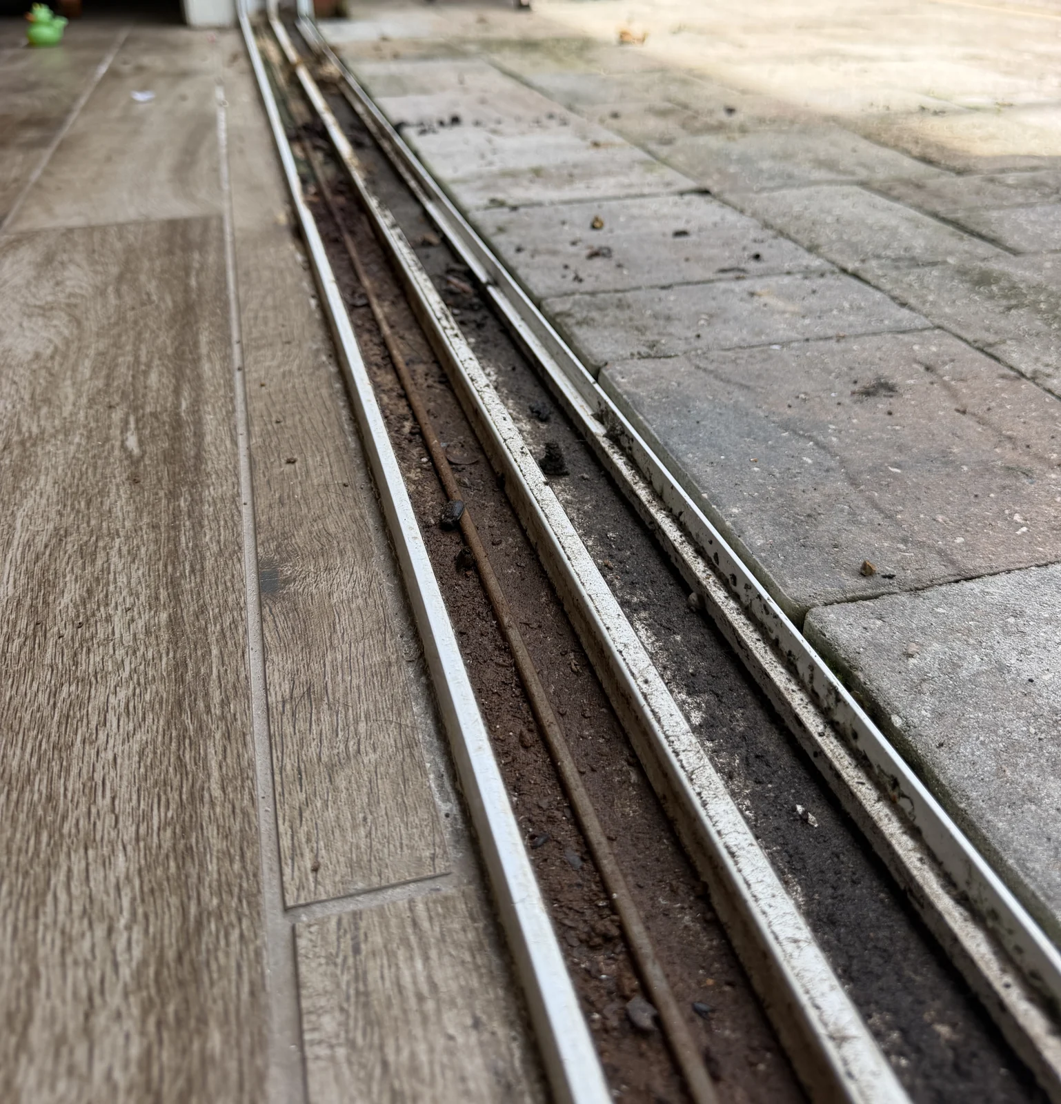 Sliding door bottom track packed with sand and grit before cleaning, Central Florida