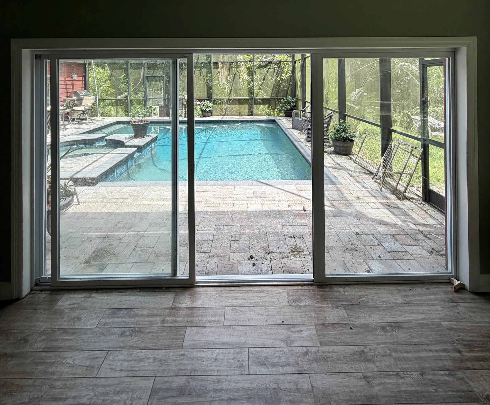 Wide-open sliding glass door framing a screened Central Florida pool lanai