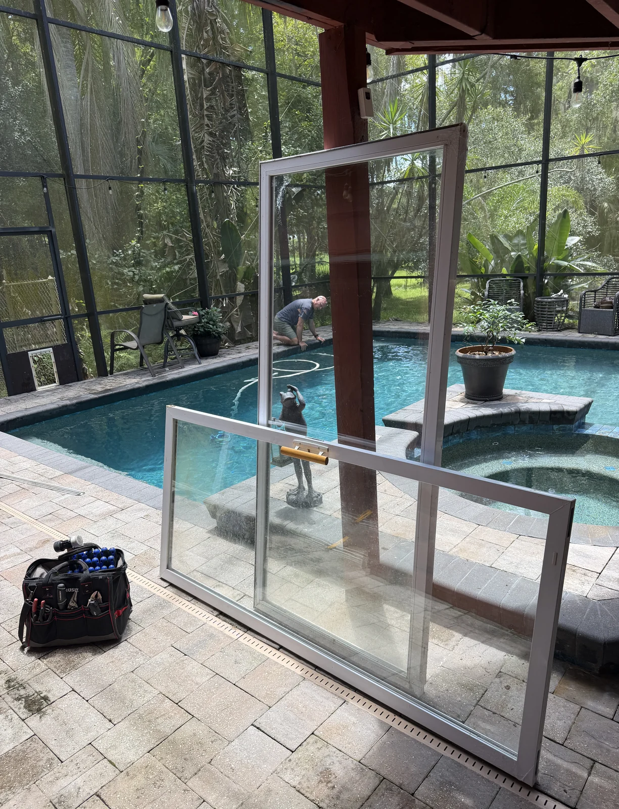 Sliding glass door panel lifted out beside a screened pool during restoration, Central Florida