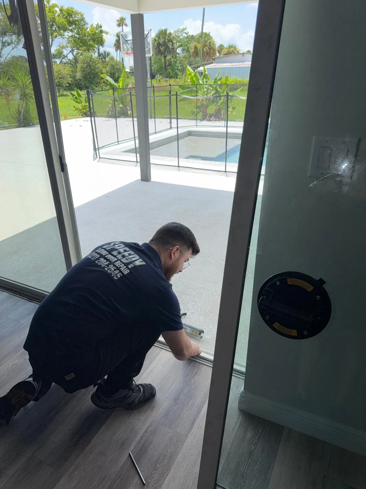 Speedy technician repairing a sliding glass door beside a pool in Central Florida