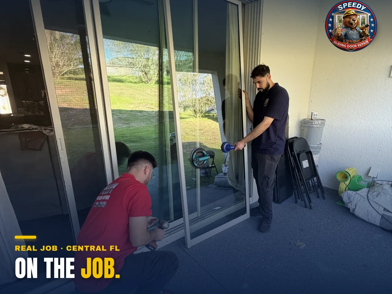 Two Speedy technicians working a sliding glass door together — one drilling the track, one on suction cups — Central Florida