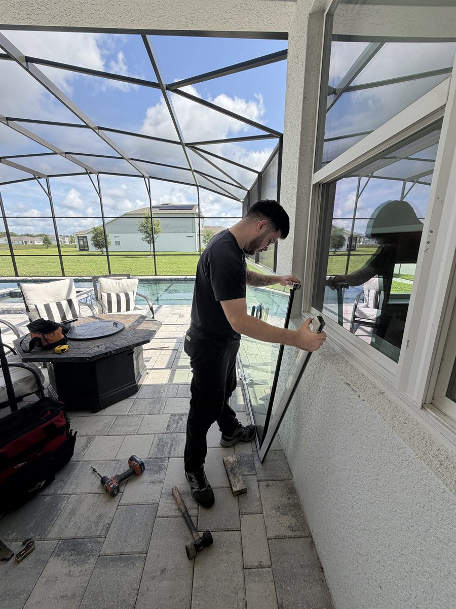 A Speedy technician lifting out a sliding glass door panel during a full restoration on a pool lanai — Speedy Sliding Door Repair, Gotha FL